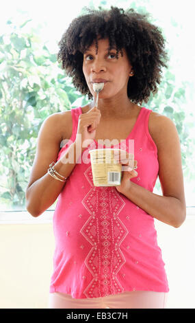 Pregnant African American mother eating ice cream from carton Stock Photo