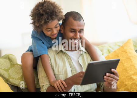 Father and son using digital tablet together in living room Stock Photo