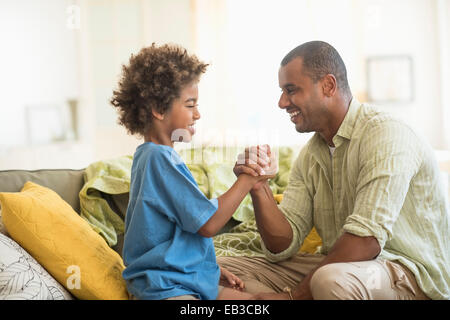 Father and son arm wrestling in living room Stock Photo