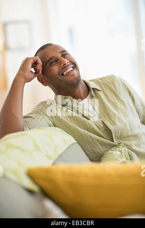 Mixed race man smiling in living room Stock Photo