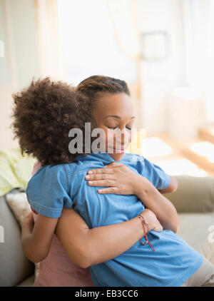 Mother and son hugging on sofa in living room Stock Photo