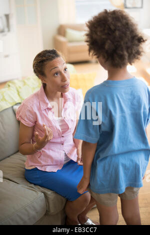 Mother talking to son in living room Stock Photo