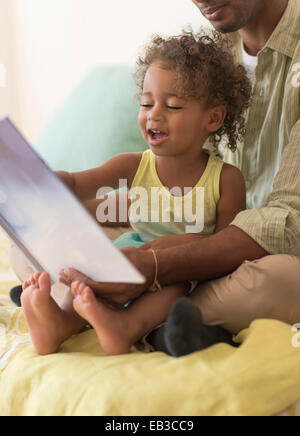 Father and daughter reading book on bed Stock Photo