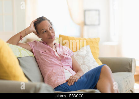 Mixed race woman smiling on sofa Stock Photo
