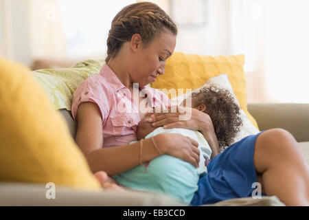 Mixed race mother nursing daughter in living room