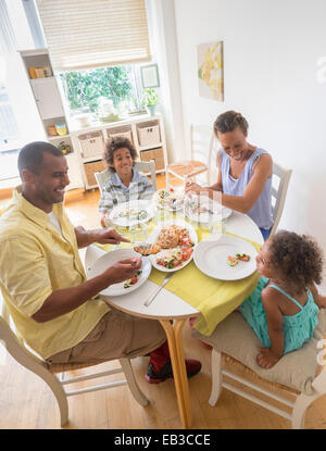 Mixed race family eating at dining room table Stock Photo