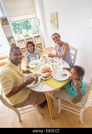 Mixed race family smiling at dining room table Stock Photo