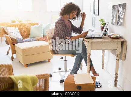 Mixed race woman using laptop in living room Stock Photo
