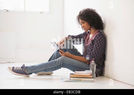Mixed race college student using digital tablet on floor Stock Photo