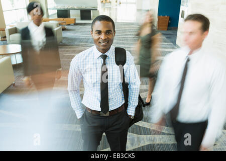 Businessman standing still in busy office lobby Stock Photo