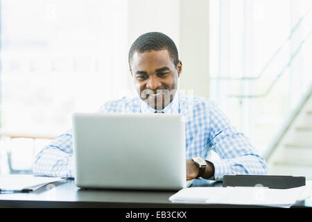 Black businessman using laptop computer at desk in office Stock Photo