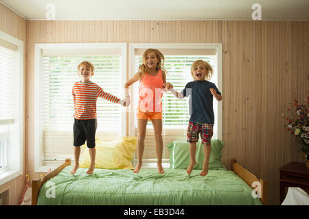 Caucasian children jumping on bed Stock Photo