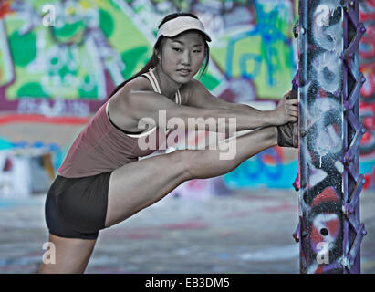 Korean runner stretching on column with graffiti Stock Photo