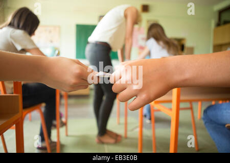 Students passing notes in classroom Stock Photo