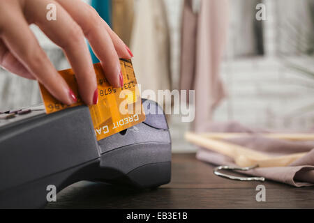 Woman swiping credit card through credit card reader Stock Photo