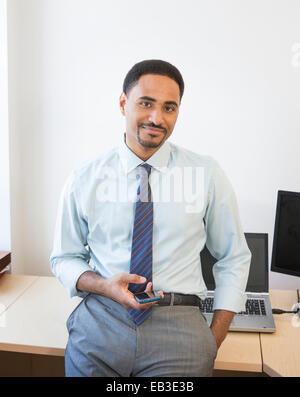Black businessman holding cell phone in office Stock Photo
