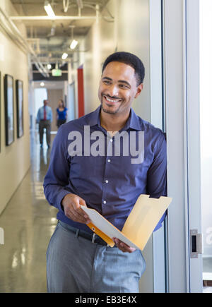 Black businessman holding folder in office hallway Stock Photo