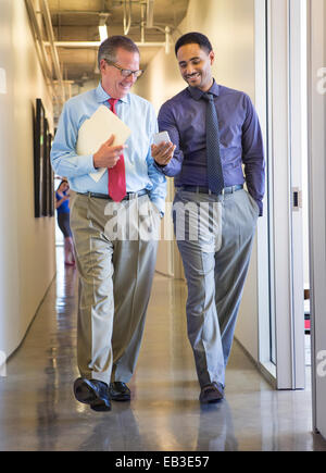 Businessmen using cell phone in office hallway Stock Photo