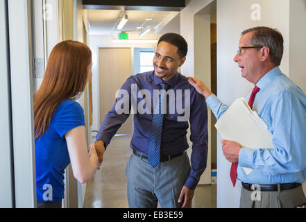 Business people shaking hands in office hallway Stock Photo
