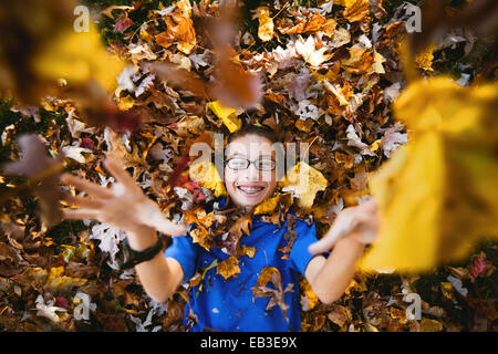 Boy lying on his back playing with autumn leaves Stock Photo