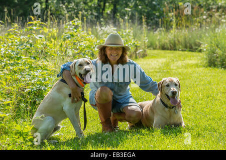 Caucasian woman petting dogs in garden Stock Photo
