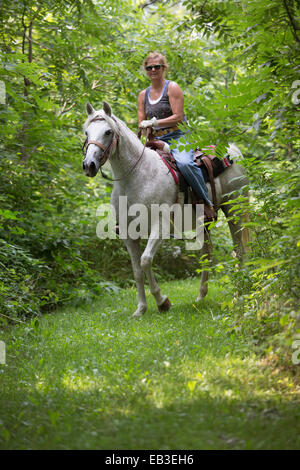 Caucasian woman riding horse in rural field Stock Photo