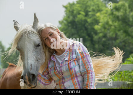 Older Caucasian woman petting horse outdoors Stock Photo