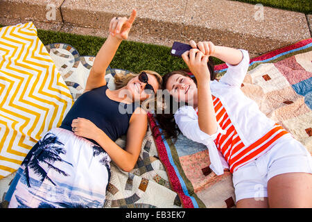 Caucasian teenage girls laying on picnic blankets in park Stock Photo