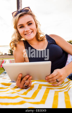 Caucasian teenage girl using tablet computer in park Stock Photo