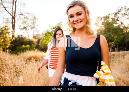 Caucasian teenage girls walking in tall grass in field Stock Photo