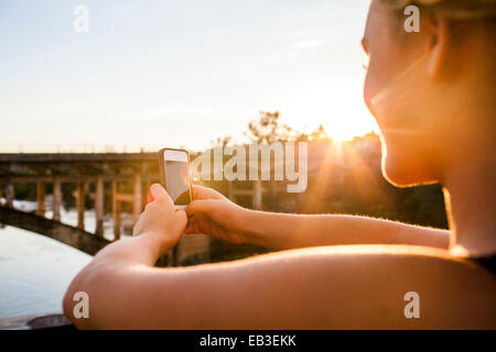 Caucasian teenage girl taking cell phone photograph of bridge Stock Photo