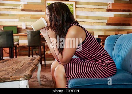 Hispanic woman drinking coffee in cafe Stock Photo