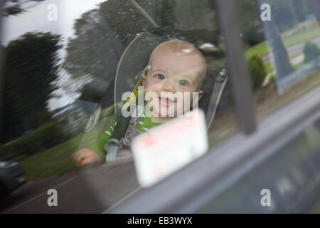 Baby boy looking out through car window Stock Photo
