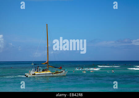 Catamaran tour boat and surfers, Waikiki, Honolulu, Oahu, Hawaii, USA
