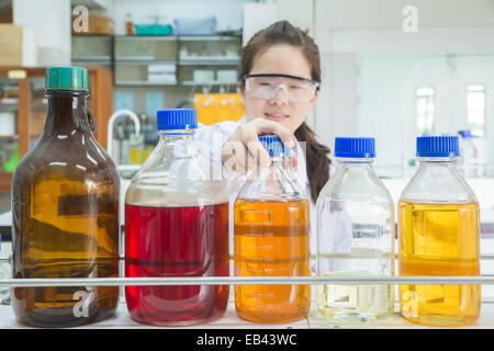 Asian scientist selecting bottle in shelf at laboratory (focus at bottle) Stock Photo