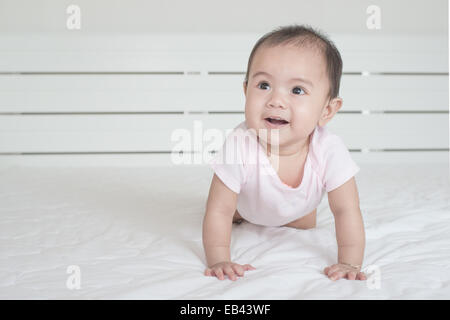 Asian baby crawling in bedroom Stock Photo