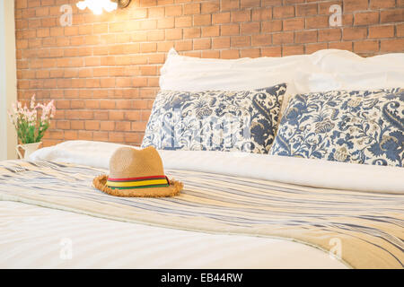 female hat and pillow on the bed of a hotel room Stock Photo