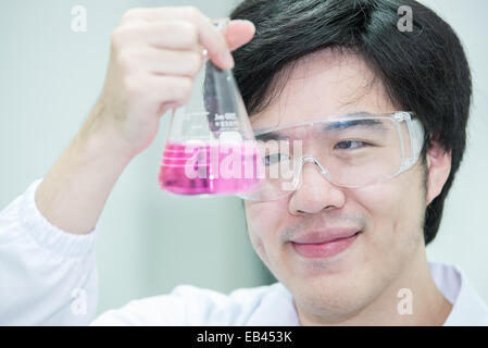 Asian scientist working in the lab,examines a test tube with liquid Stock Photo
