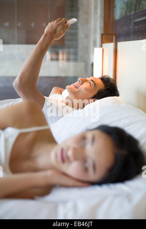 Young man using smart phone on bed Stock Photo