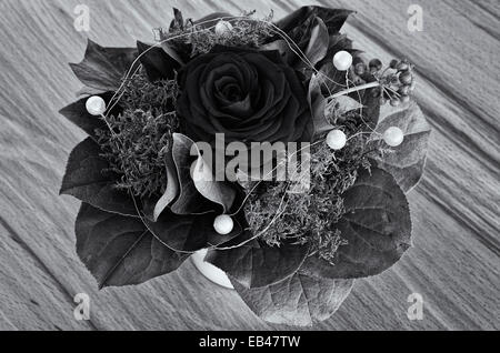 Single rose with greens and deco beads in a bouquet, black and white. Stock Photo