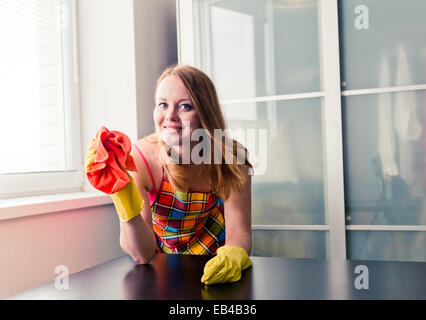 Happy girl cleaning table with furniture polish at home Stock Photo