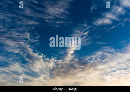 Sunset touches the wispy leading edge of a cirrus clouds. Stock Photo