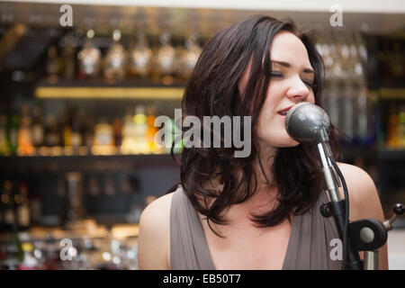 Brunette haired woman singing in a microphone Stock Photo