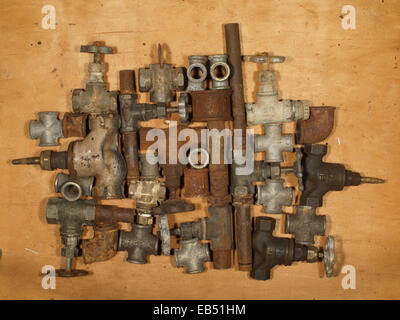 Various old and rusty fittings and valves arranged on a wooden table. Stock Photo