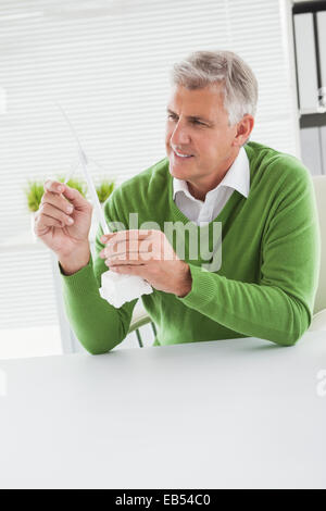 Casual businessman looking at model wind turbine Stock Photo