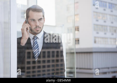 Businessman looking out window on the phone Stock Photo