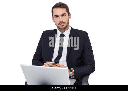 Cheerful businessman with laptop using smartphone Stock Photo