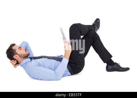 Businessman lying on floor using tablet Stock Photo