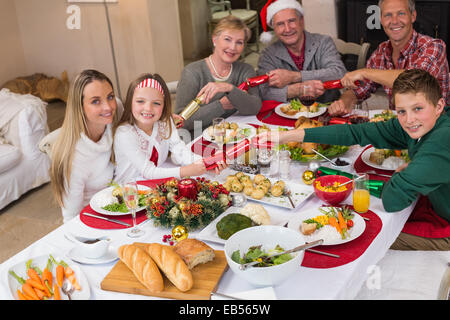 Smiling family pulling christmas crackers at the dinner table Stock Photo