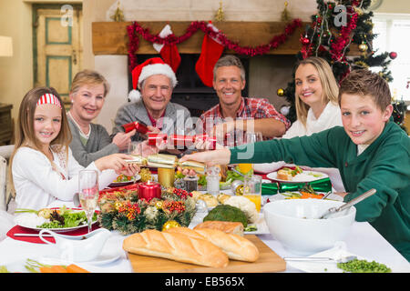 Smiling family pulling christmas crackers at the dinner table Stock Photo